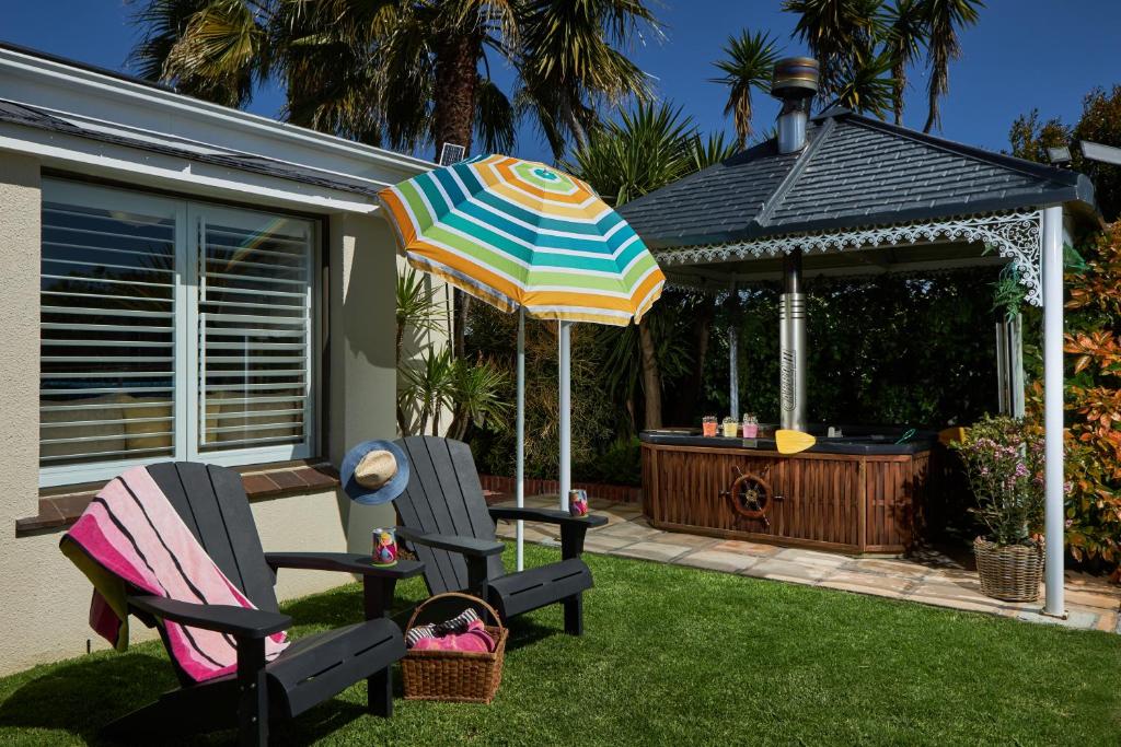 a patio with two chairs and an umbrella and a gazebo at Meerendal Cottage-Affordable Luxury,Private Pool in Cape Town