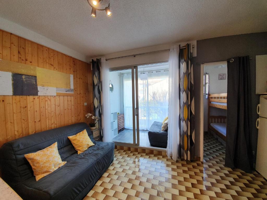 un salon avec un canapé et une porte coulissante en verre dans l'établissement Valras-plage studio cabine 100m de la plage, à Valras-Plage