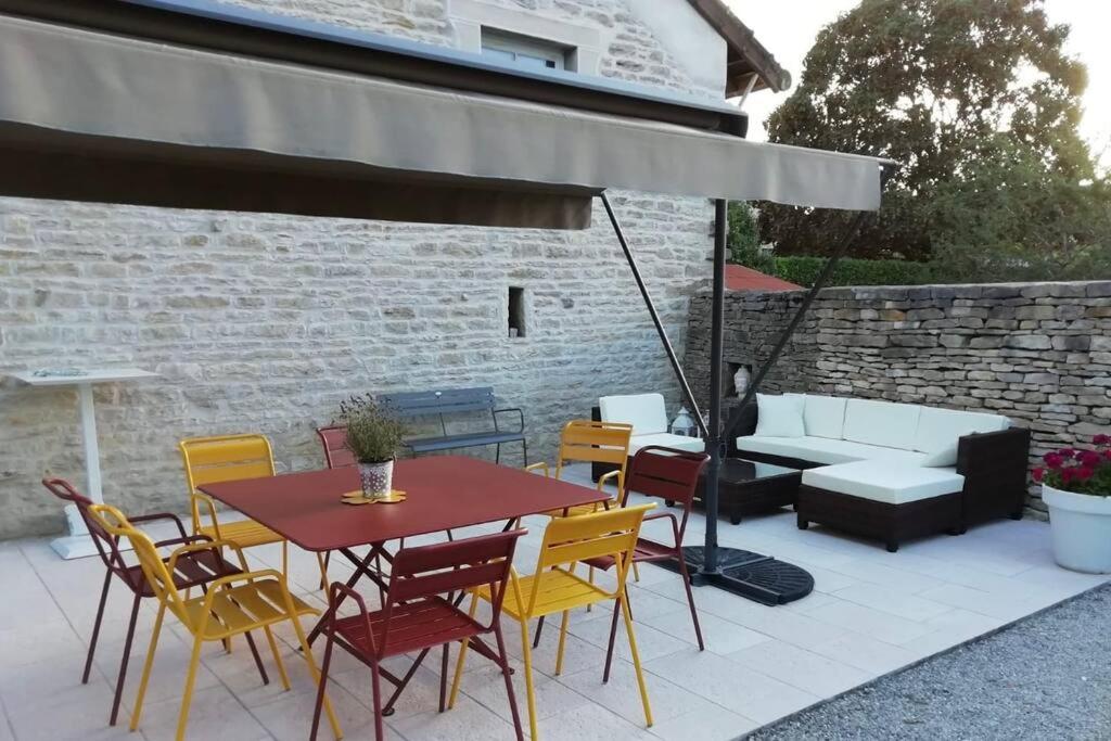 a patio with a table and chairs and an umbrella at Bienvenue au Gite La So Sweet in Rully