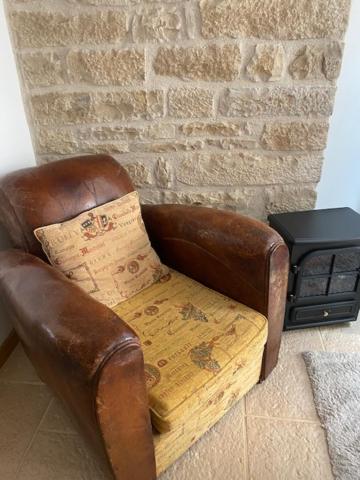 a leather chair with a pillow in front of a brick wall at Bienvenue au Gite La So Sweet in Rully