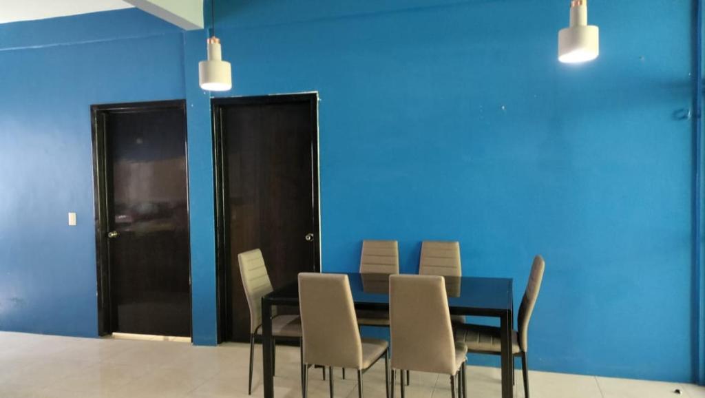 Juchitán de ZaragozaにあるCasa la flor de lotoの青い壁のダイニングルーム(テーブル、椅子付)