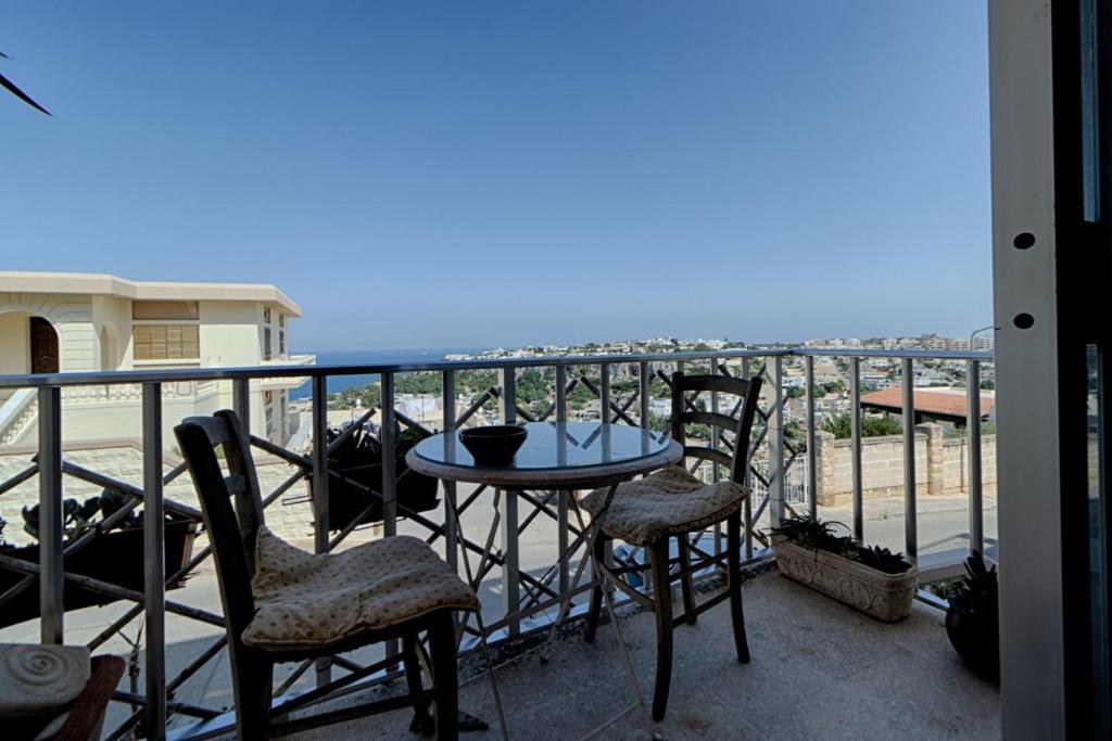 a balcony with a table and chairs and the ocean at sunrise flats in Mellieħa