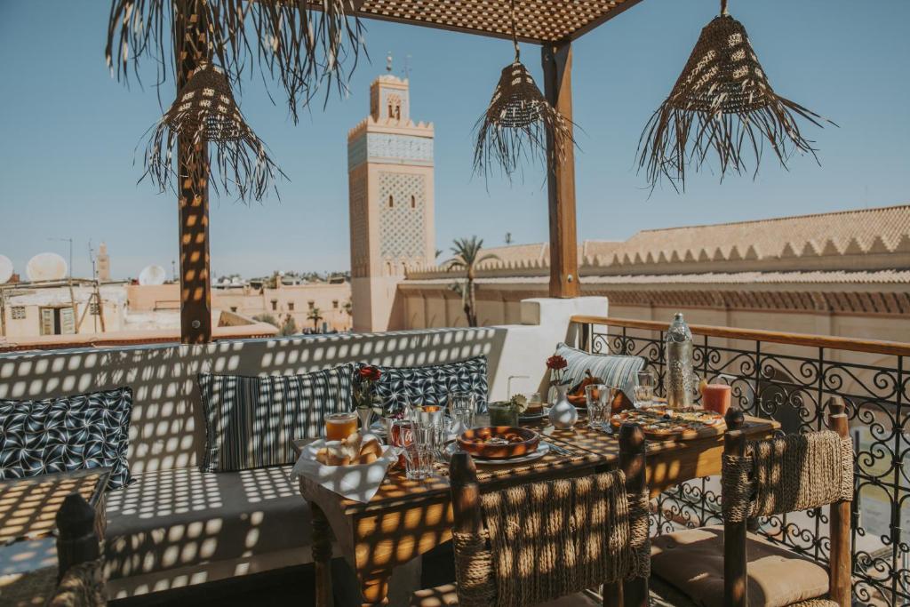 a table with food on a balcony with a clock tower at Riad Casa Kasbah in Marrakech