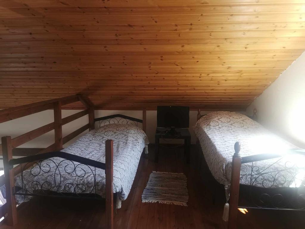 two beds in a room with a wooden ceiling at The Mouflon House Pedoulas in Nicosia