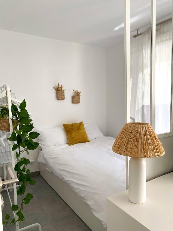 a white bedroom with a bed and a lamp at Appartement terrasse proche Centre in Montpellier