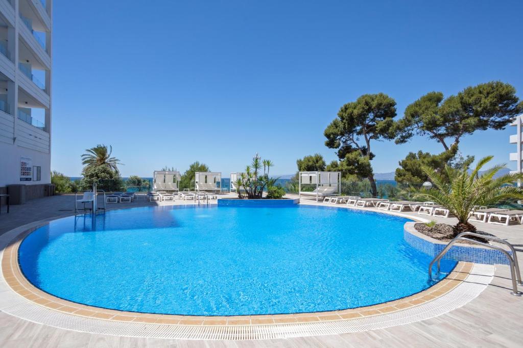 uma grande piscina azul com cadeiras e árvores em Hotel Best Punta Dorada em Salou