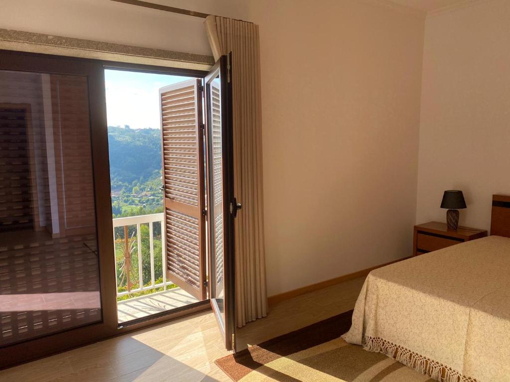 a bedroom with a bed and a window with a view at Quinta da Travessa in Cinfães