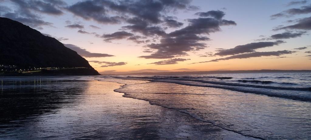 einen Sonnenuntergang am Strand mit dem Meer in der Unterkunft 13 Cambrian Court in Penmaen-mawr