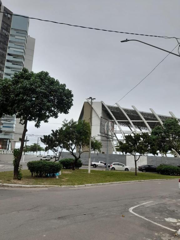 a large building with trees in front of a street at Suíte Itaipu Mar in Vila Velha
