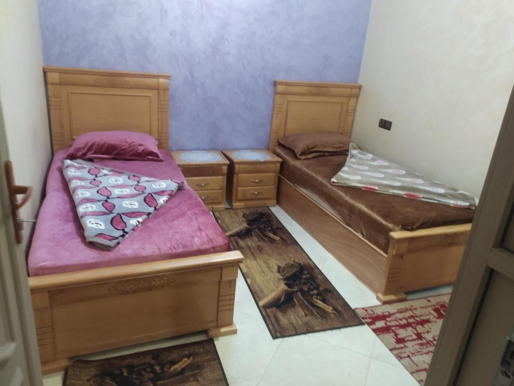 2 camas individuales en una habitación con paredes moradas en شقق فندقية بن خليل /hôtel appartements Bin khlil, en Tan-Tan