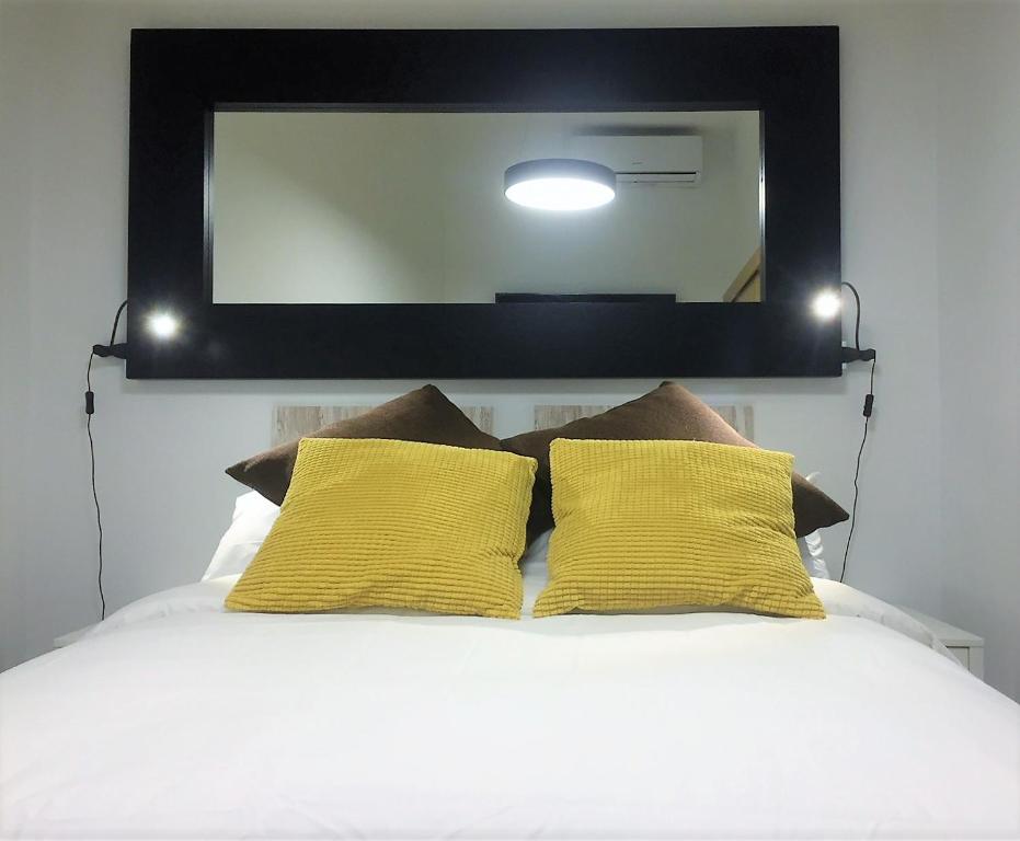 a mirror above a bed with two yellow pillows at Paz y calma en Madrid centro in Madrid