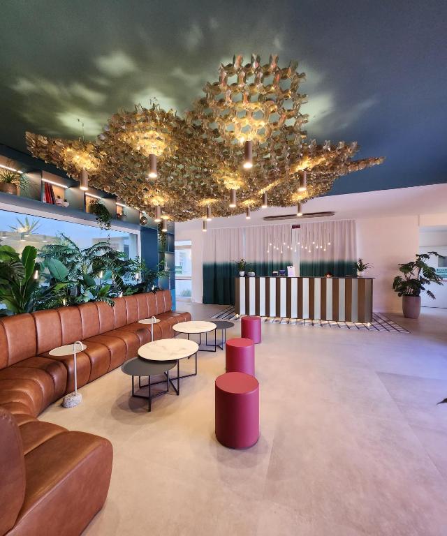 a lobby with a couch and tables and plants at Hotel Imperial in Bologna
