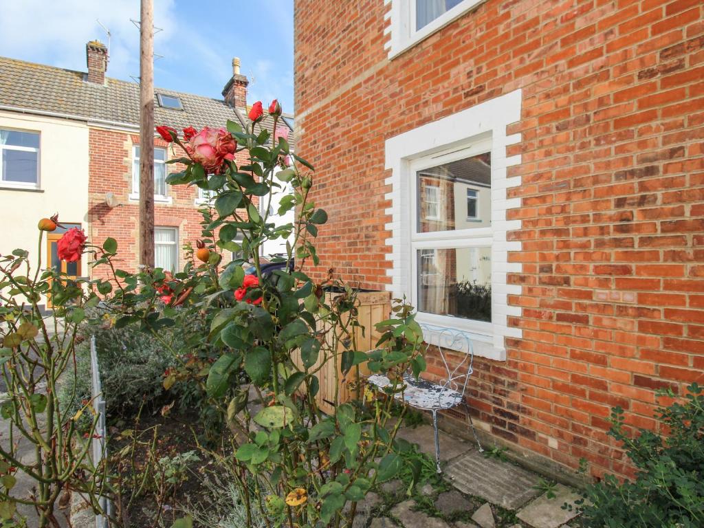 un rosier devant un bâtiment en briques dans l'établissement The Corner House, à Weymouth