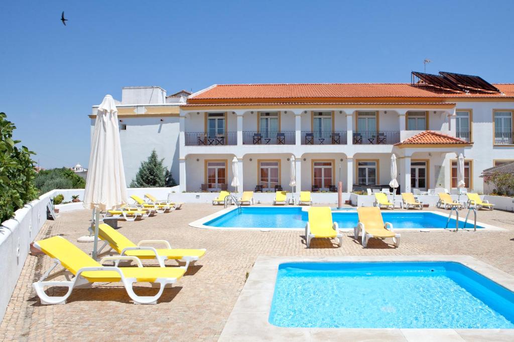 a villa with a swimming pool and lounge chairs and a house at Convento D'Alter Hotel in Alter do Chão