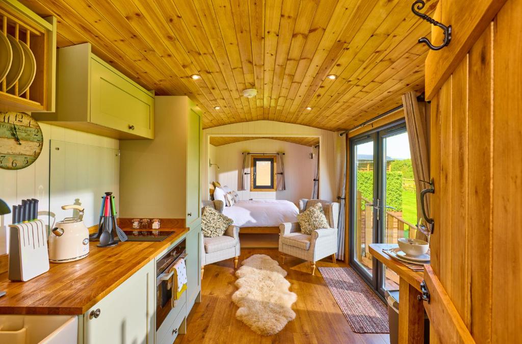 a kitchen and living room with a bed in a room at Abberley Shepherds Hut - Ockeridge Rural Retreats in Wichenford