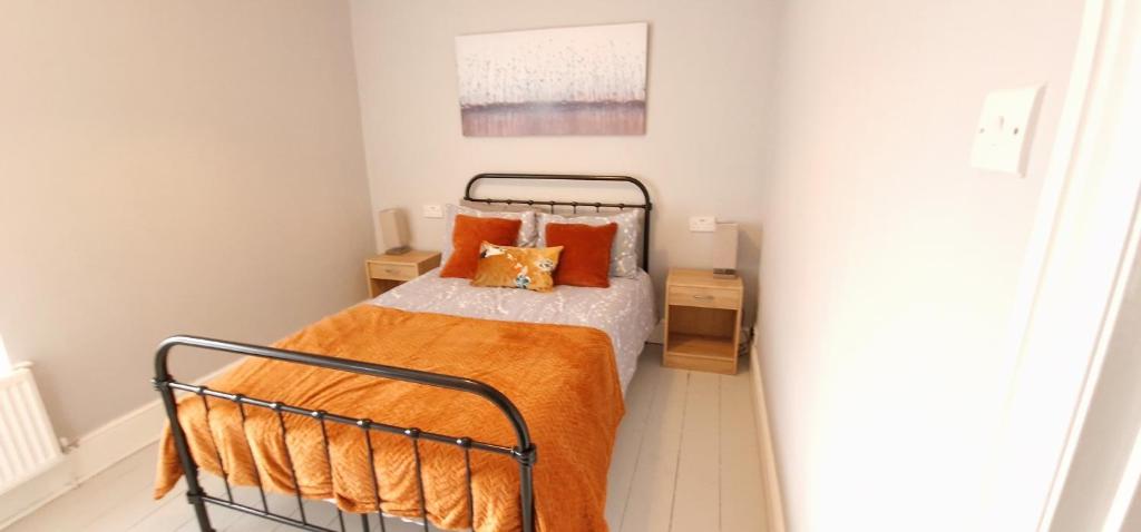 Dormitorio pequeño con cama con almohadas de color naranja en Cheerful 2 bed home with mountain views en Blaenau-Ffestiniog
