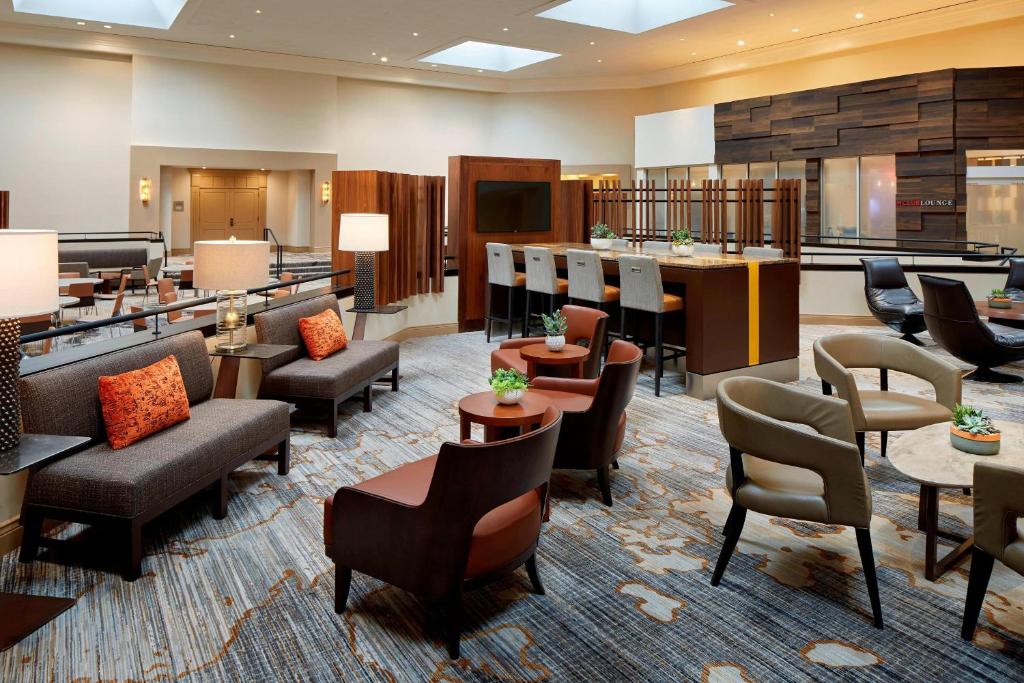 a lobby with a waiting area with chairs and tables at Marriott Birmingham Grandview in Acton