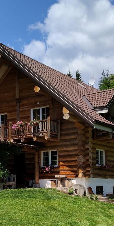 una baita di tronchi con balcone sul lato. di Chalet le Dorf a Nötsch