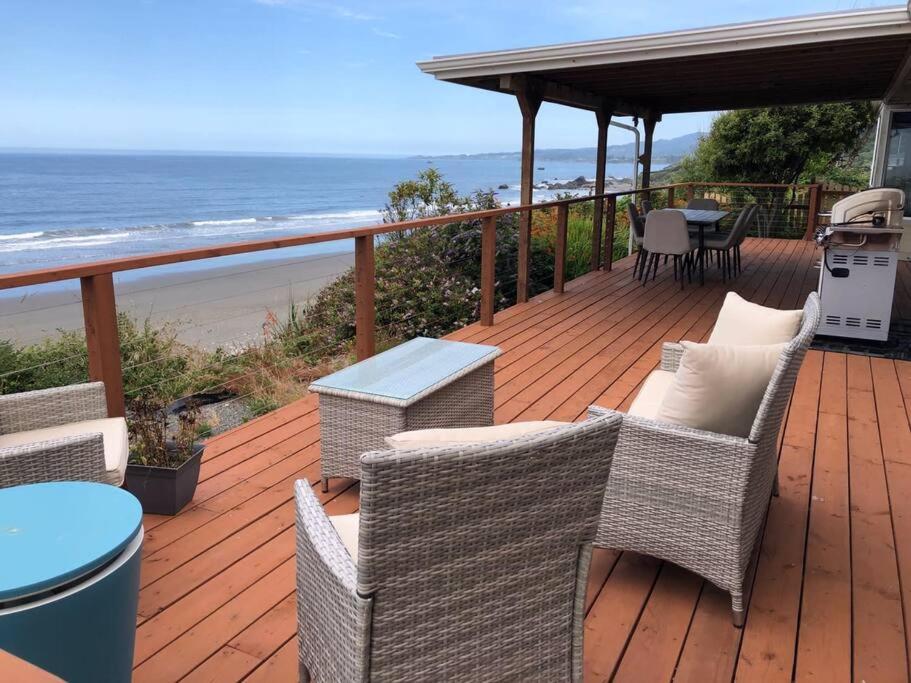 una terraza con sillas y una mesa y la playa en Redwood Coast Beach Front Home California, en Smith River