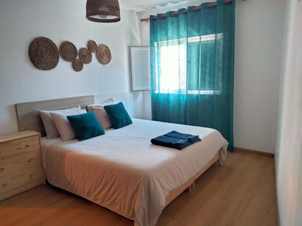 una camera da letto con un grande letto con una tenda blu di Casa dos Rosas a Melides