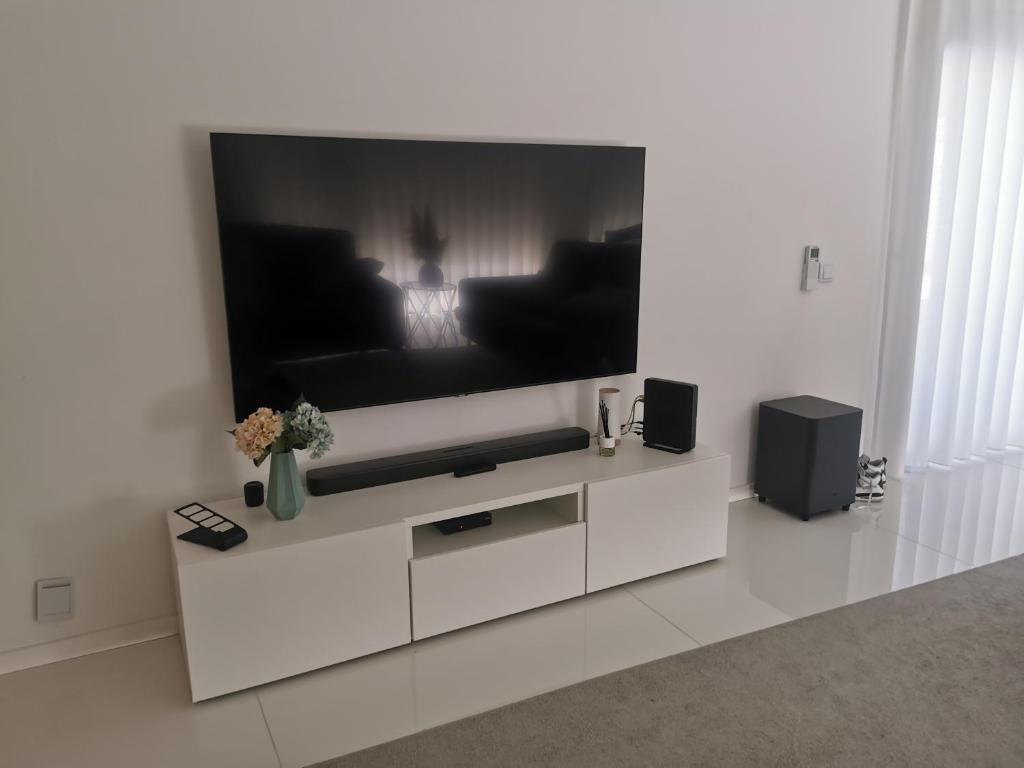 Sala de estar blanca con TV grande en la pared en Vila Amares, en Amares