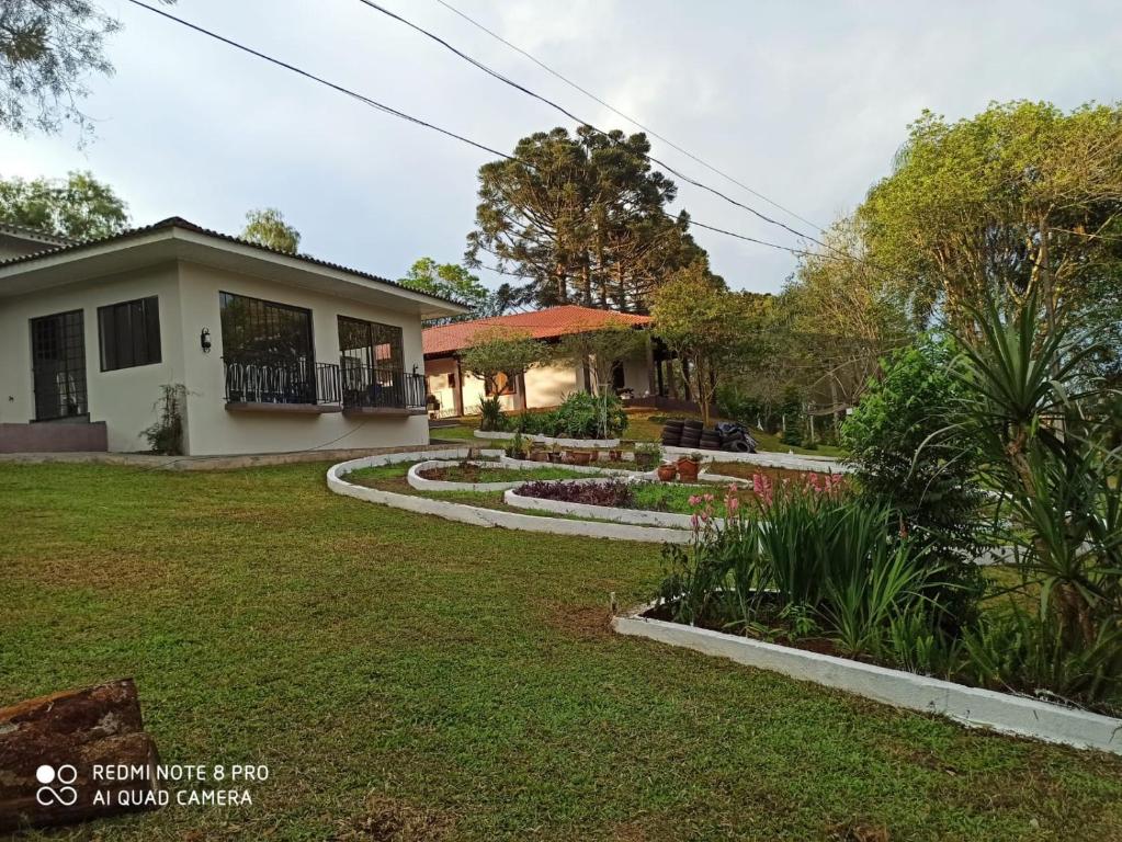 a house with a garden in front of it at Chácara ADLUC in Cascavel