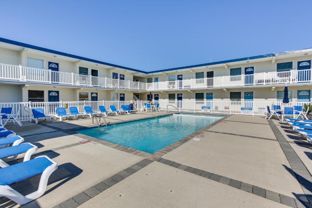 a swimming pool with lounge chairs in front of a hotel at Wildwood Crest Condo Rental Walk to Beach! in Wildwood Crest