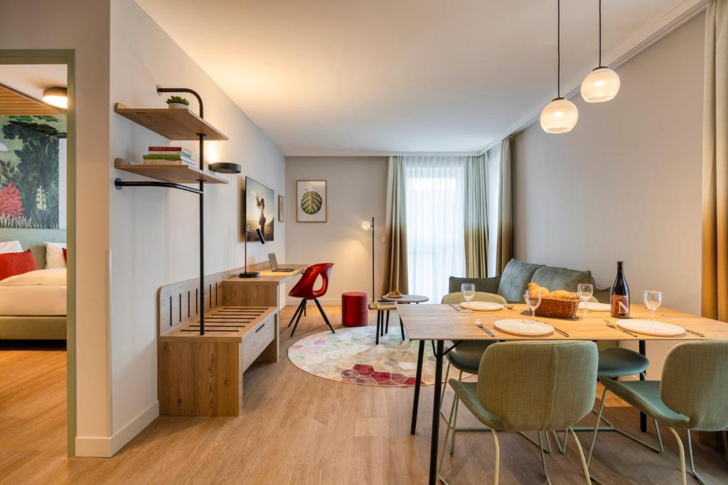 a dining room and living room with a table and chairs at Citadines Danube Vienna in Vienna