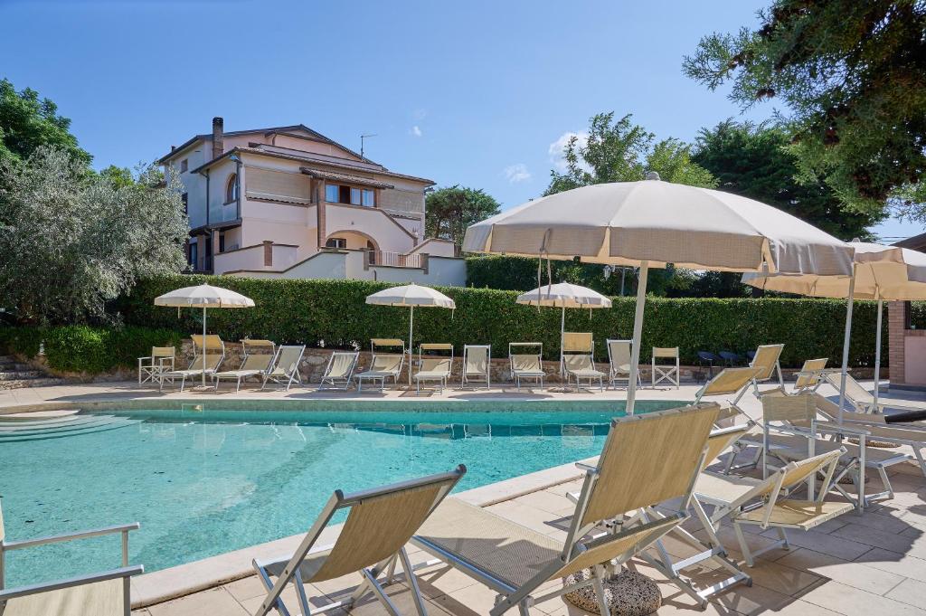 a group of chairs and umbrellas next to a swimming pool at Verde - Euroappartamenti in San Vincenzo