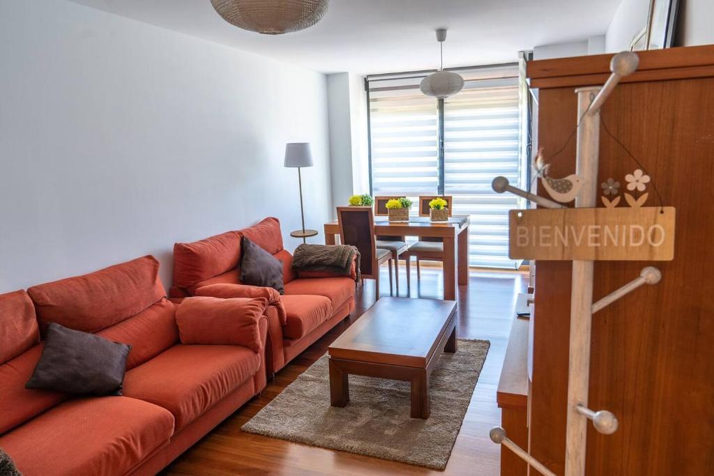 een woonkamer met een rode bank en een tafel bij Piso nuevo cerca de Santander in Soto de la Marina