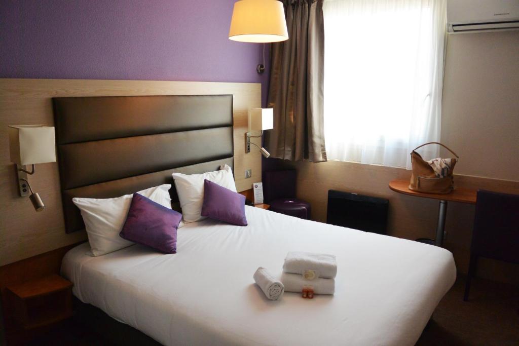een hotelkamer met een groot wit bed en 2 handdoeken bij The Originals City, Au Relais Saint-Éloi, Tours (Inter-Hotel) in Tours
