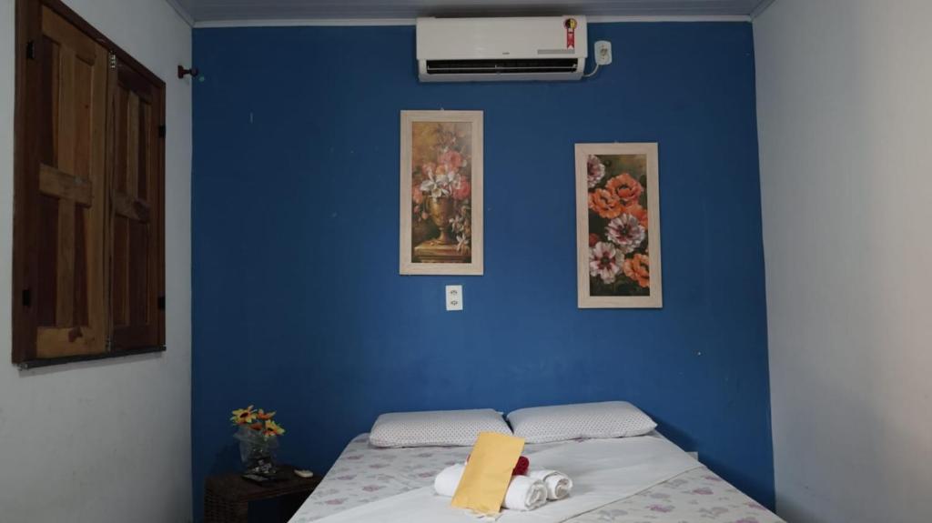 uma parede azul com uma cama num quarto em pousada chykos em Barreirinhas