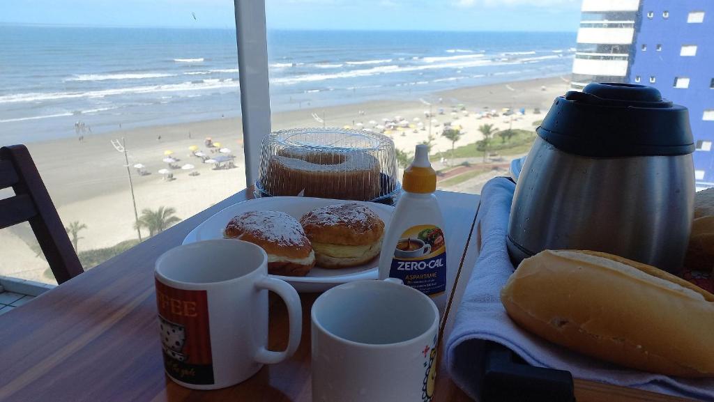 ein Tablett mit Donuts und Getränken auf einem Tisch am Strand in der Unterkunft Apartamento na Praia Grande II - Pé na Areia in Praia Grande