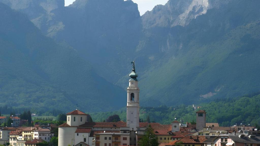 eine Stadt mit einem Uhrturm vor einem Berg in der Unterkunft Villa Trequattrini 