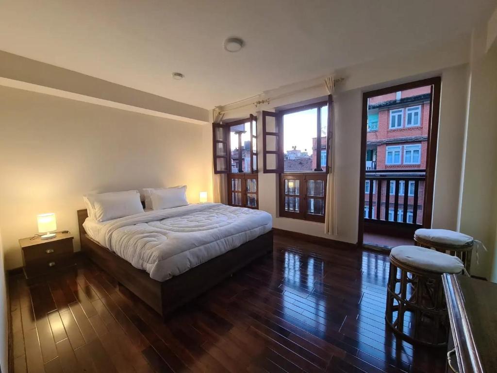 una camera con un letto e due grandi finestre di Dalucha Heritage Home a Patan