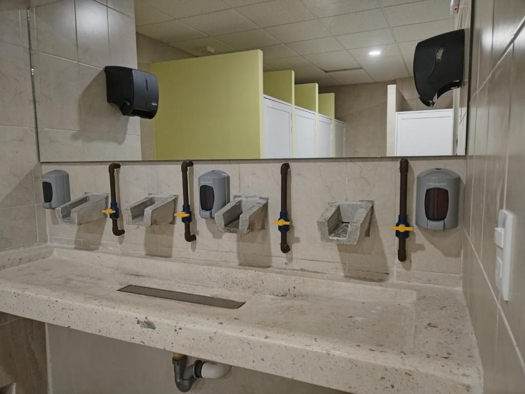 a row of urinals in a public bathroom at Hostel Tropico 20 PDC in Playa del Carmen