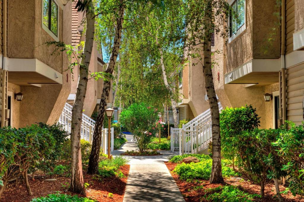 a walkway between two buildings with trees at Residence Inn San Jose Campbell in Campbell