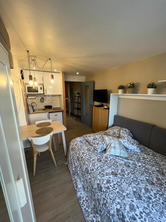 a bedroom with a bed and a table and a kitchen at STUDIO COSY STRASBOURG CENTRE TRAM in Strasbourg
