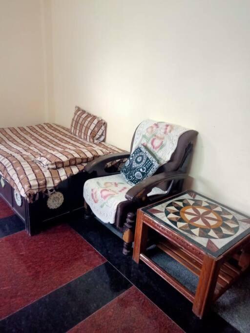 a room with a chair and a bed and a stool at home sweet home in Bhopal
