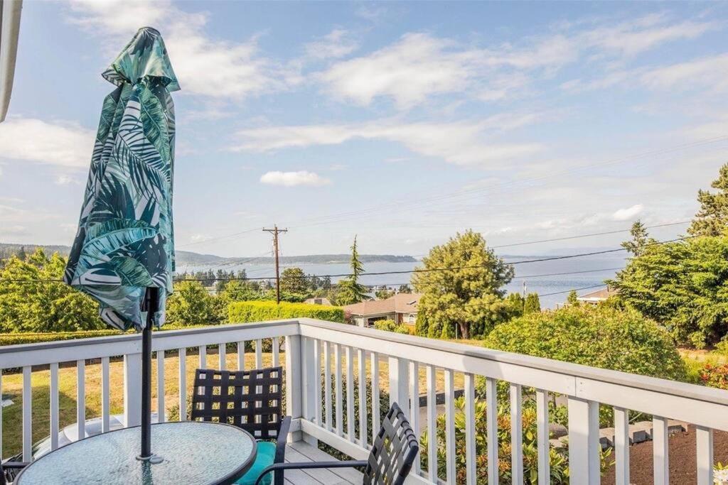 a table with an umbrella on a balcony at Charming beach home with Ocean & Mt. Baker View in Camano