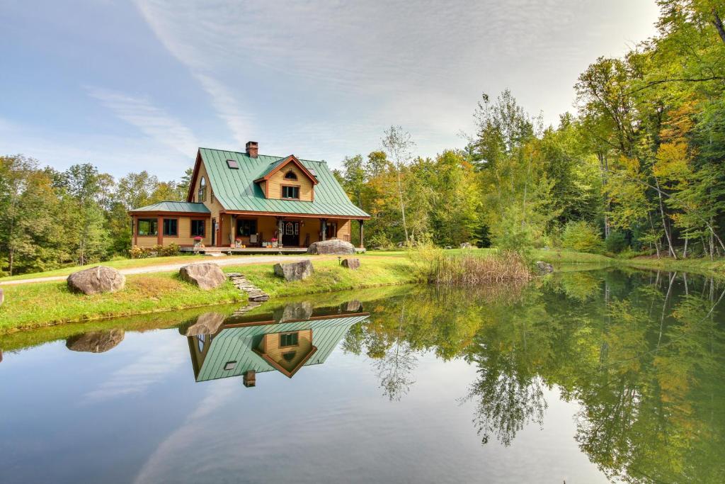 a house with a green roof next to a lake at Chester Home with Views about 10 Mi to Okemo Mtn Resort! in Chester