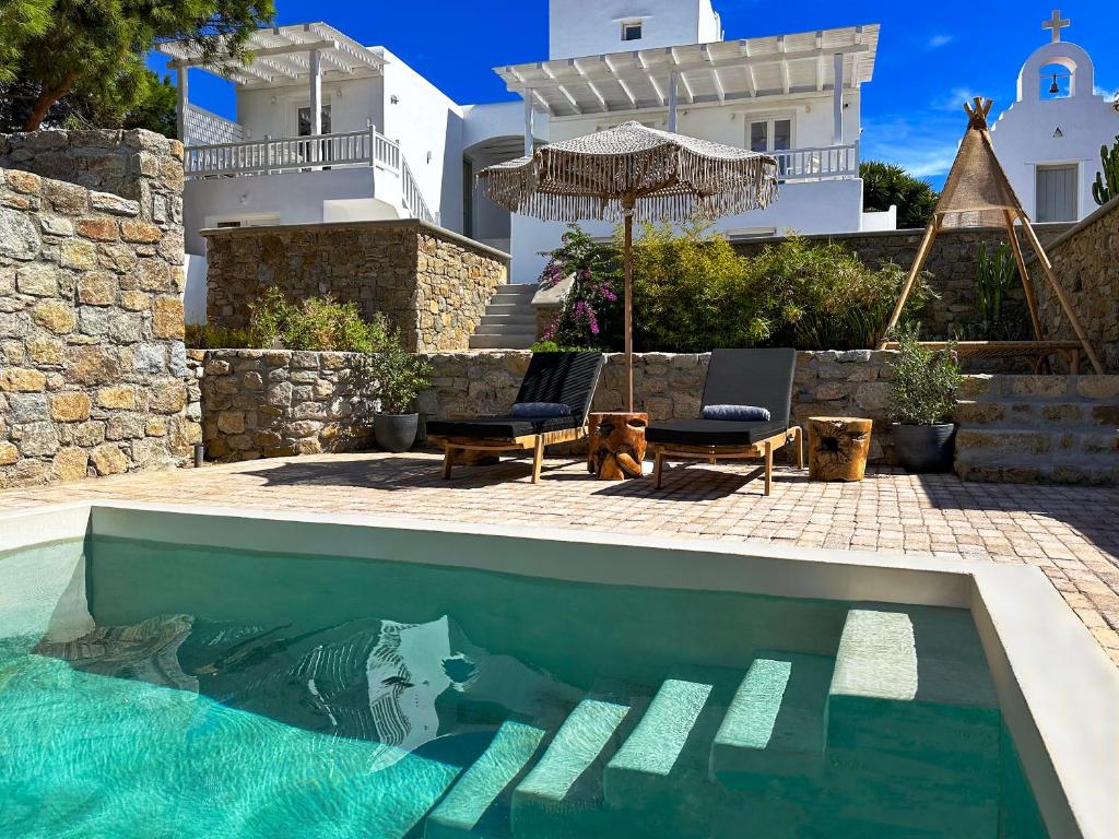 una piscina con 2 sillas y una sombrilla y una casa en Sofos Suites Mykonos, en Mykonos ciudad