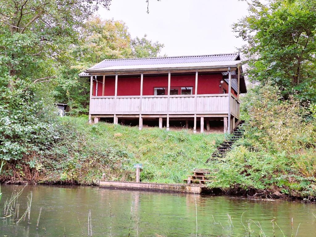 Brinken at Ry في Ry: منزل احمر على تل بجوار نهر
