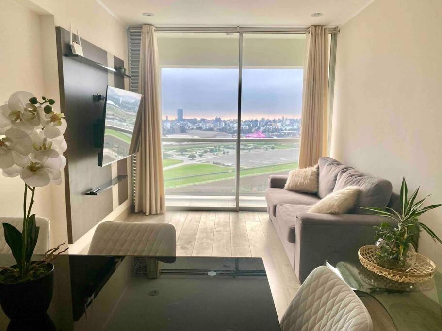 a living room with a couch and a large window at Dpto con hermosa vista al hipódromo de Monterrico in Lima