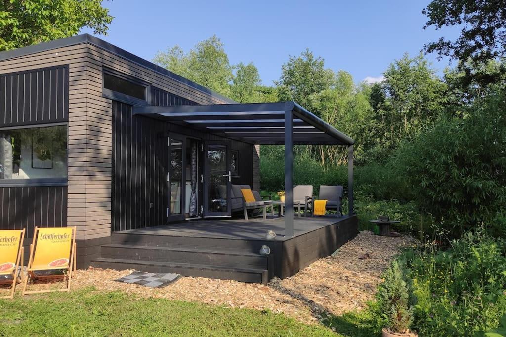 cobertizo negro con terraza con mesa y sillas en Tiny House 14 - Sollberg, en Salzhemmendorf