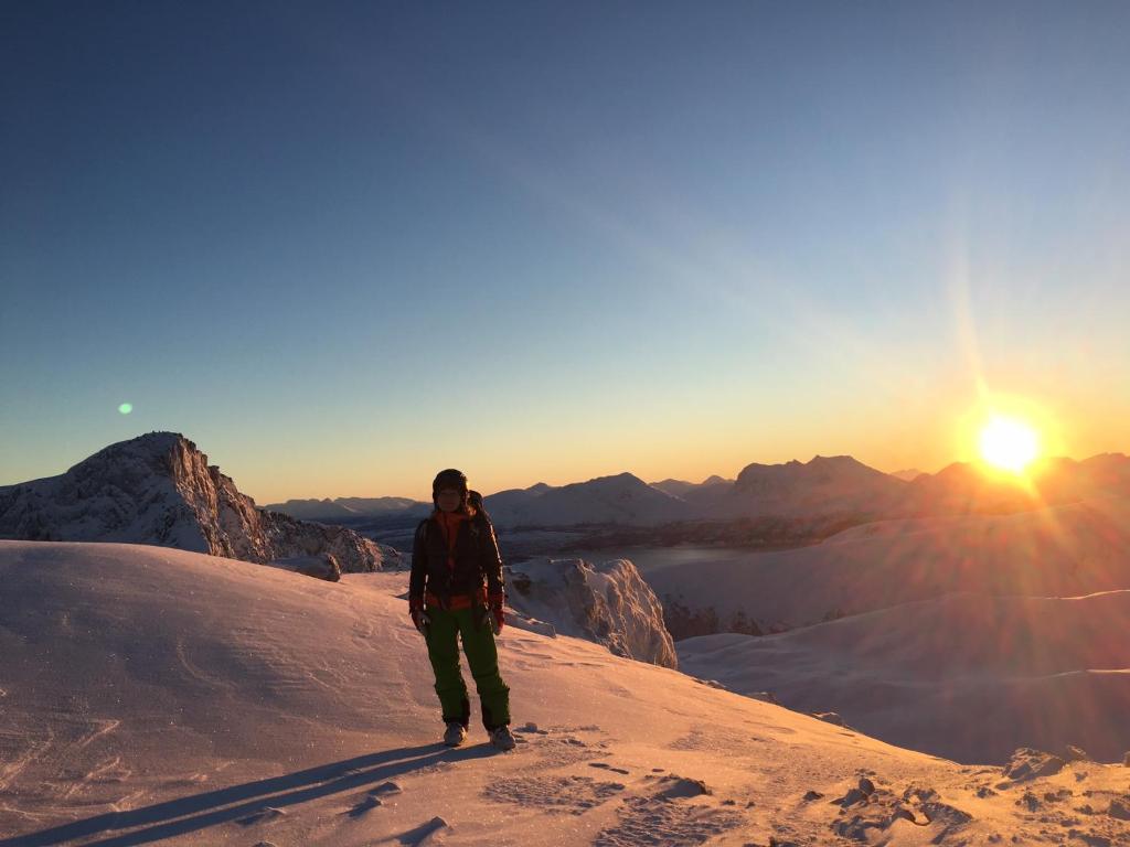 um homem parado no topo de uma montanha coberta de neve em Lena Apartment Tromsø em Kvaløya