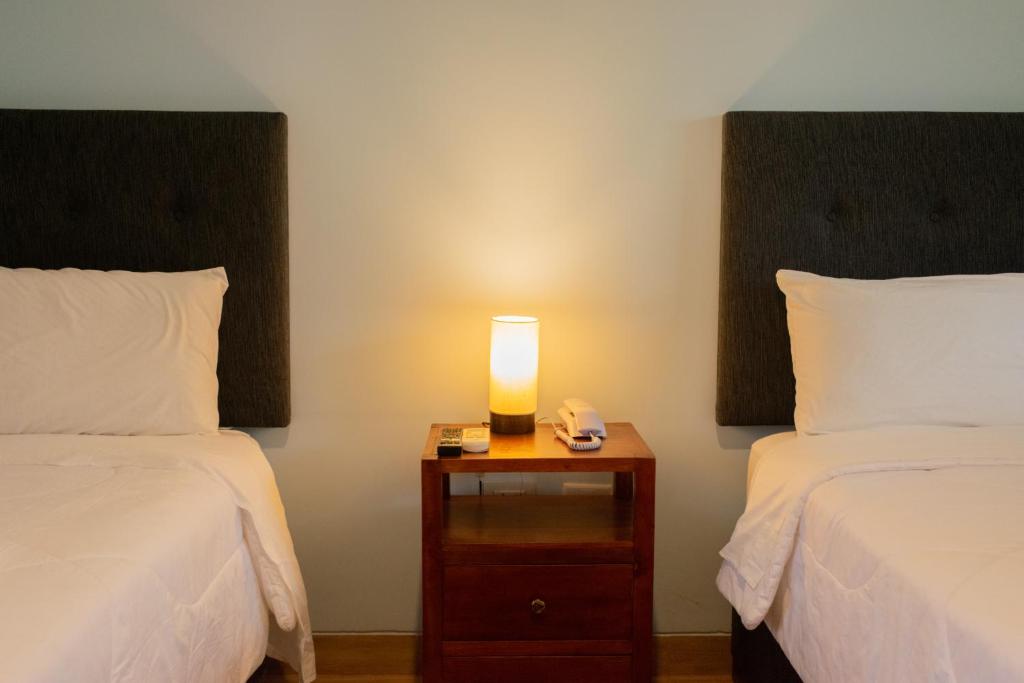 Habitación con 2 camas y mesita de noche con lámpara en Hotel Laguna Azul, en Sauce