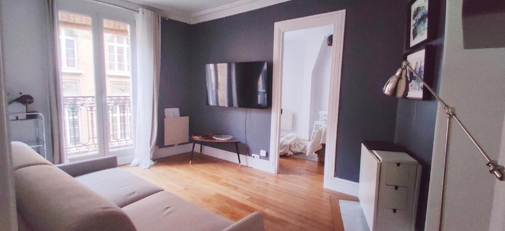 salon z kanapą i telewizorem w obiekcie Luxueux appartement Paris 17 w Paryżu
