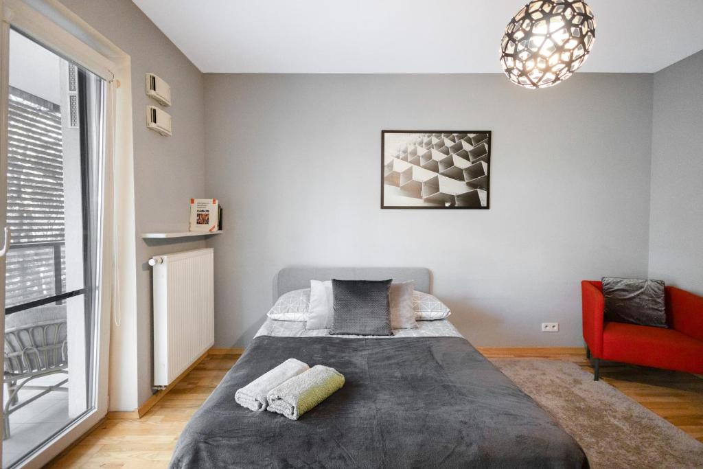 ClickTheFlat Artistic Estate Apartment في وارسو: غرفة نوم بسرير وكرسي احمر