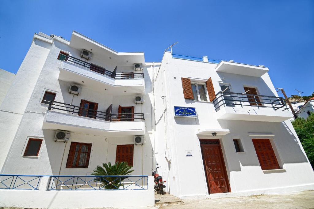 um edifício branco com portas e janelas vermelhas em To Gefyraki Rooms em Agios Kirykos